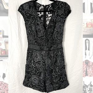 New black Bebe romper with metallic floral lace detail and satin tie